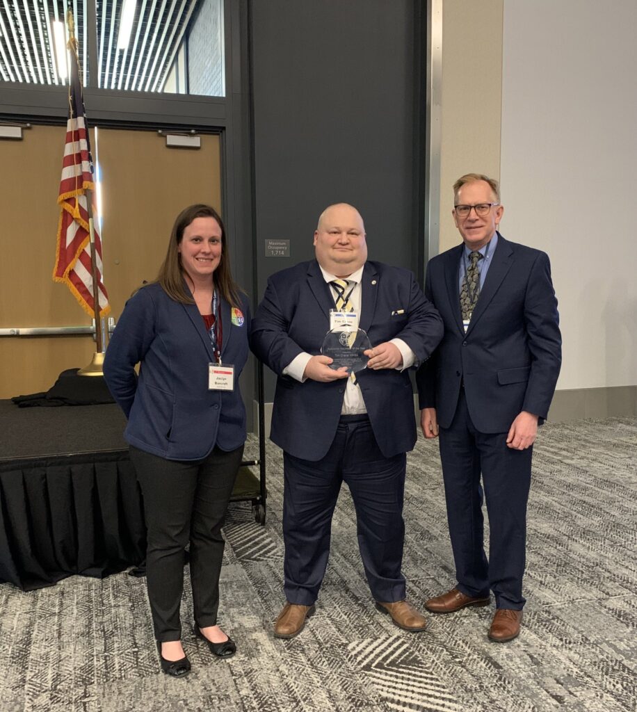 Tim Crane WM8A receives AUXCOMM Volunteer of the Year Award from the State of Michigan, presented from Jaclyn Barcroft of EMHSD and Max Schneider, ARRL SEC
